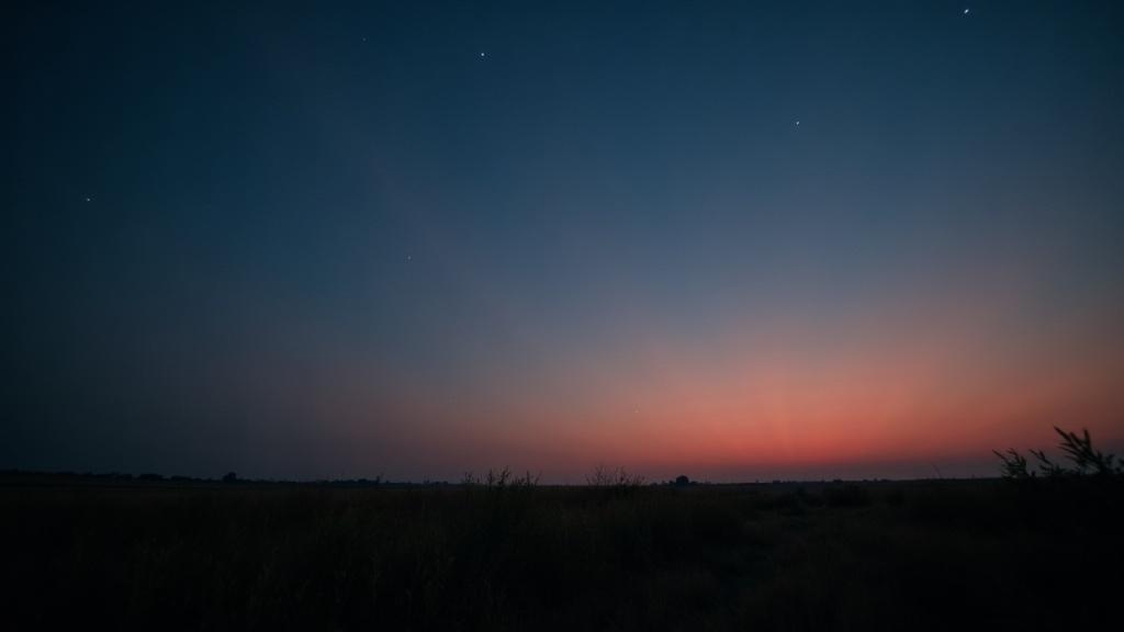 A pre-dawn sky with the horizon glowing faintly orange, stars still visible overhead, wide-angle lens, soft natural light