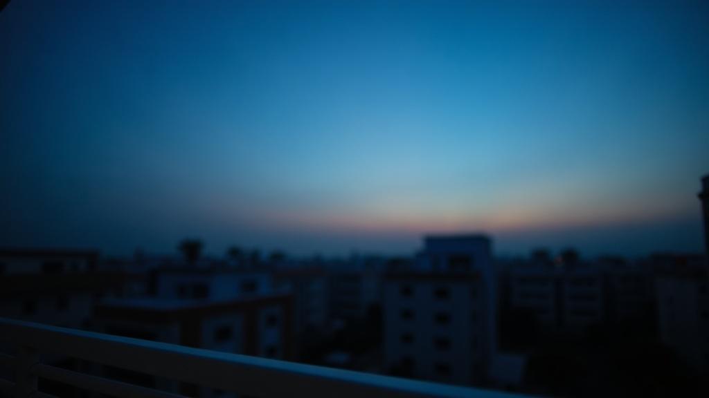 A still, pre-dawn sky with the first hint of light on the horizon, seen from a suburban balcony